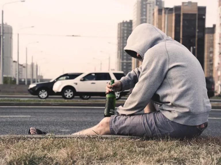 Mann mit Alkoholflasche am Straßenrand | Stimmungsbild Therapie bei Sucht: Alkohol, Suchtmittel, Glücksspiel, Drogen