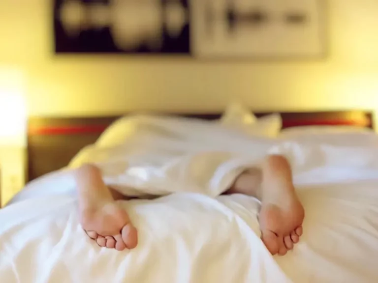 Füße ragen unter Bettdecke hervor | Stimmungsbild Psychotherapie & Coaching bei Schlafstörungen
